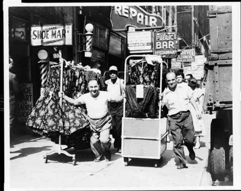 Men pull racks of clothing through the Garment District, New York City, in 1955 (Photo credit: World Telegram & Sun photo by Al Ravenna)
